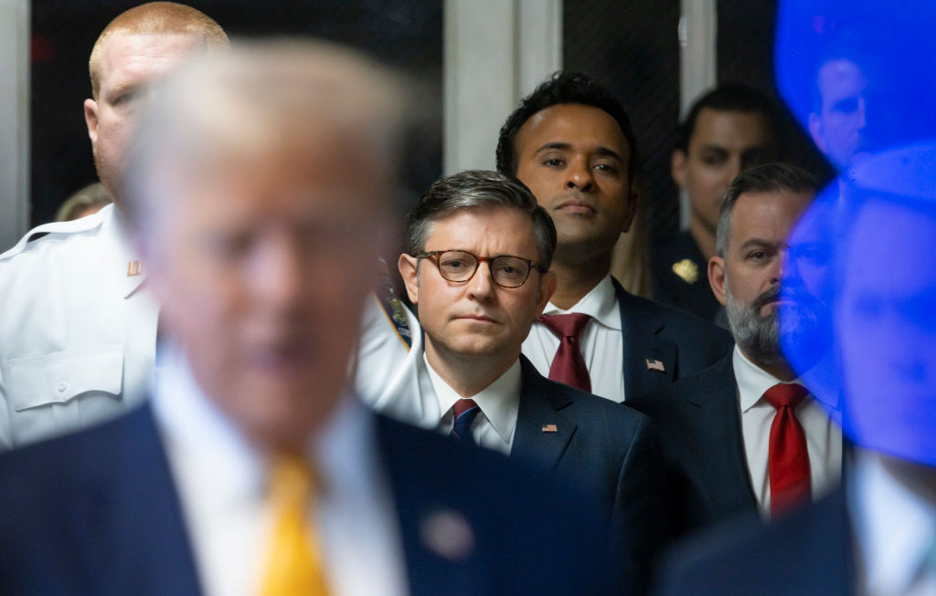 Mike Johnson behind Donald Trump